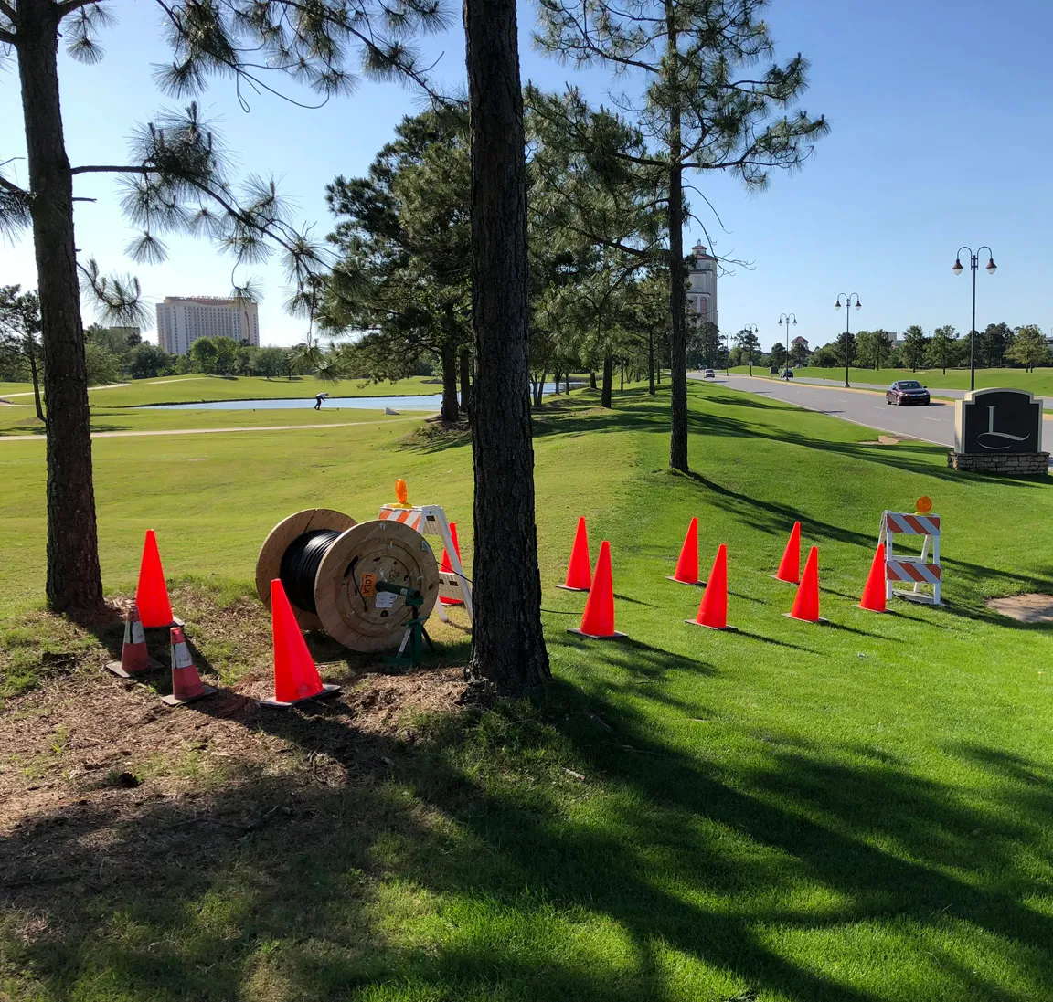Cable reel and traffic cones staged for an outdoor cable installation on a landscaped site