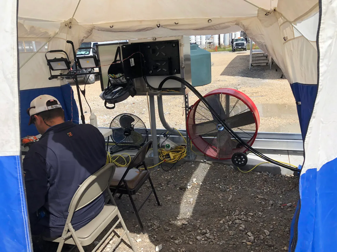 Technician working inside a field tent set up for an outdoor cable installation