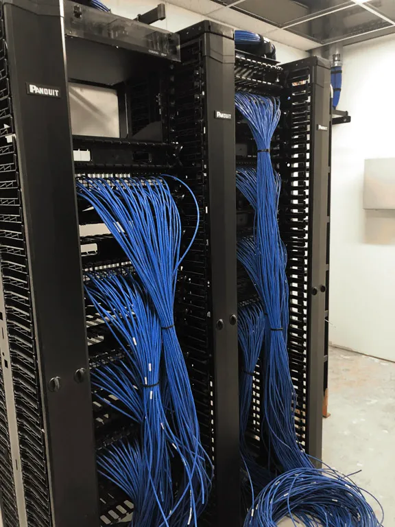Two vertical cable management racks holding large bundles of terminated network cables