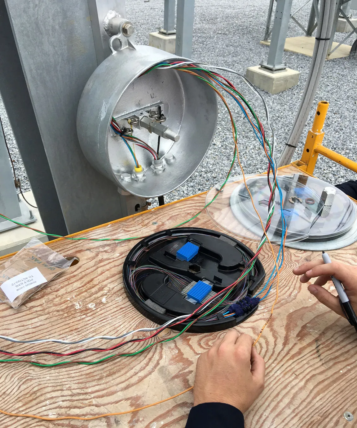 Technician splicing fiber cables inside an open pole-mounted junction enclosure
