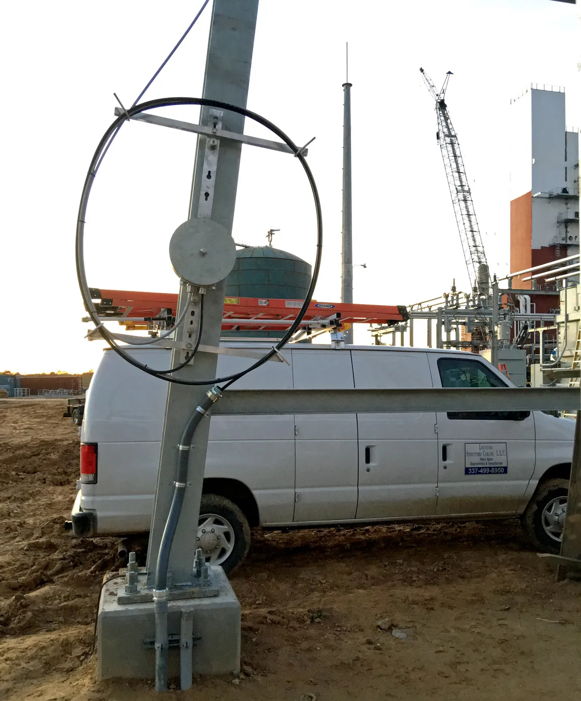 Coiled aerial cable mounted on a utility pole beside the Louisiana Structured Cabling service van