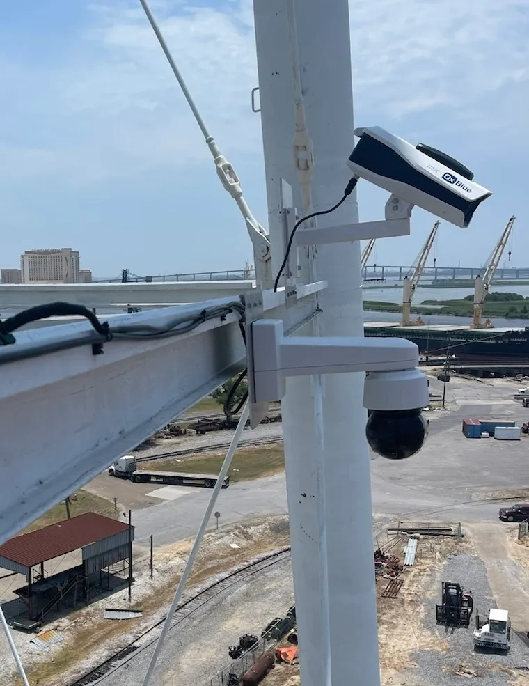 Jobsite camera mounted on a tower beam overlooking a shipyard with cranes and a cargo ship