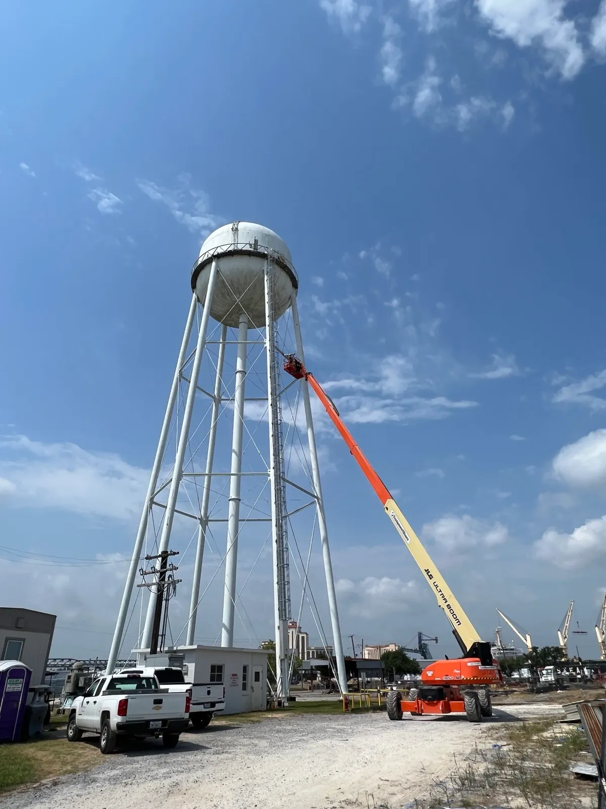 Boom lift raised alongside a water tower to install a camera on the tank