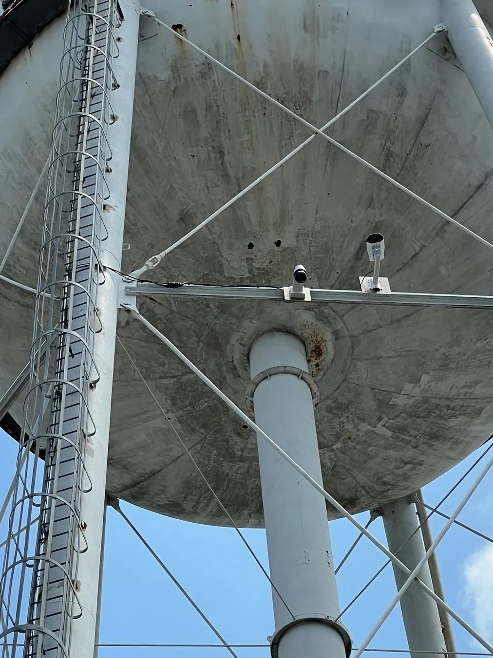 View from below a water tower tank showing two cameras mounted on the support beams